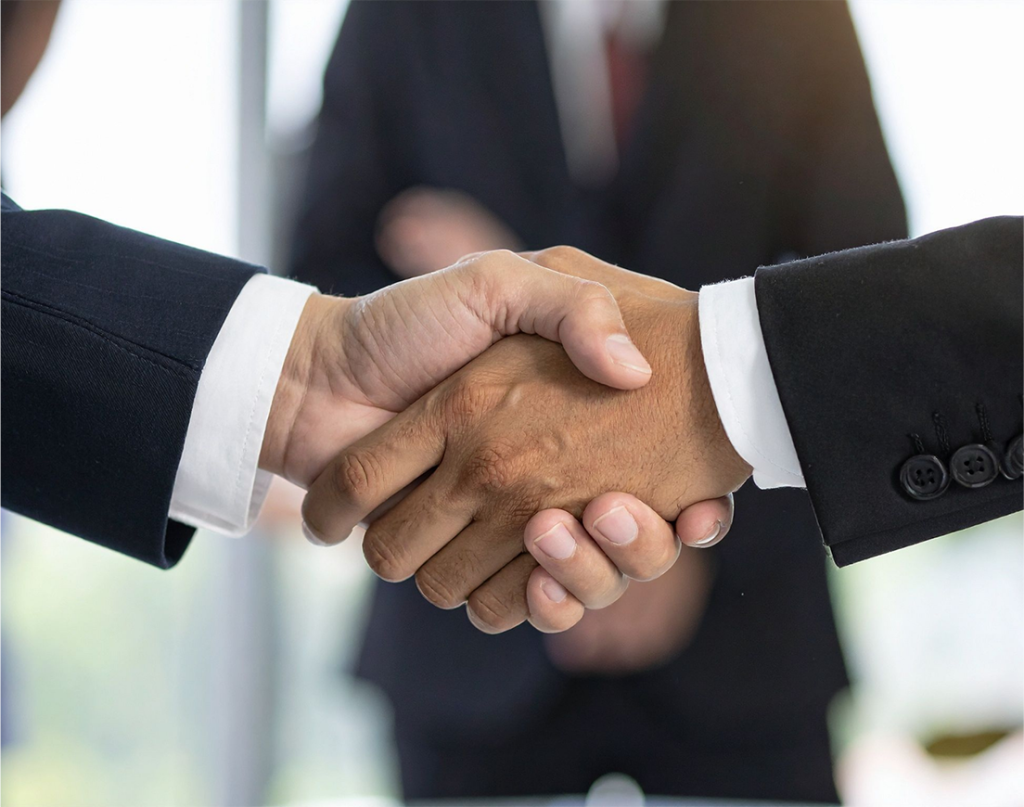 Close-up of two people in business suits shaking hands, signaling a business agreement or partnership.